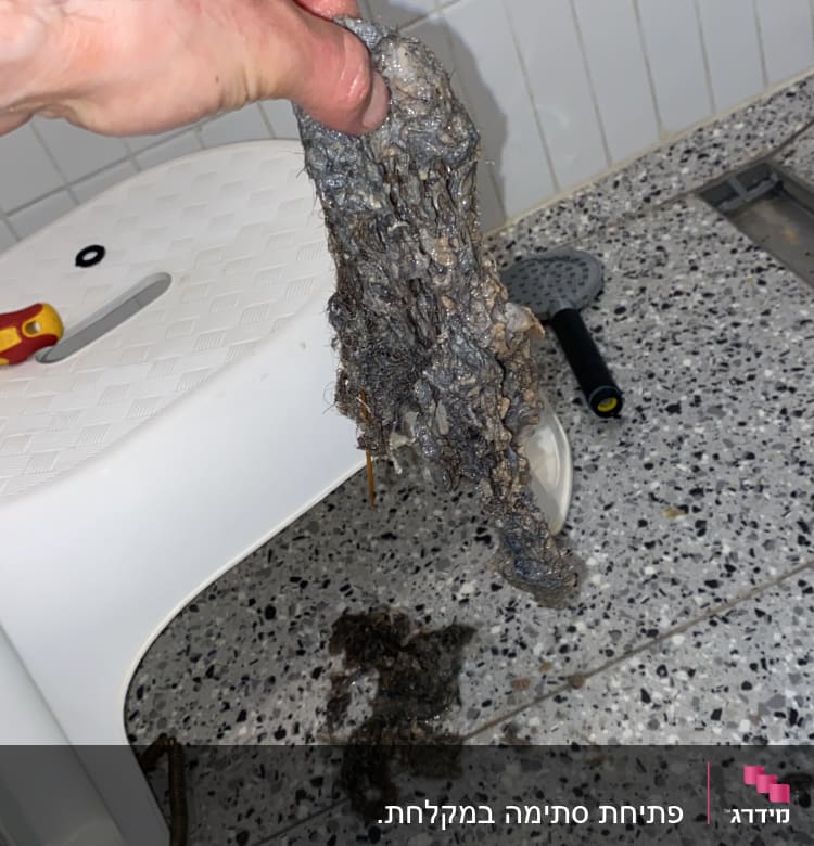 יד מחזיקה סתימה שהוצאה מצינור ביוב